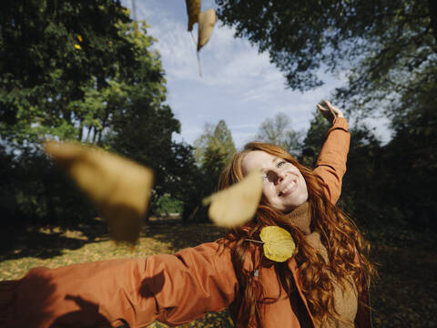 Glückliche rothaarige Frau genießt den Herbst in einem Park, lizenzfreies Stockfoto