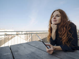 Rothaarige Frau mit Tablet auf Dachterrasse - KNSF07165