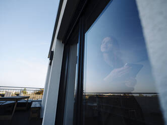 Rothaarige Frau hält Tafel hinter Fensterscheibe - KNSF07173