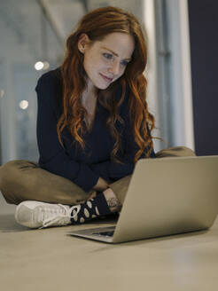 Rothaarige Frau mit Laptop auf dem Boden - KNSF07176