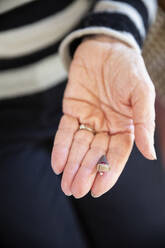 Die Hand einer älteren Frau mit einem modernen Hörgerät - MAMF01061