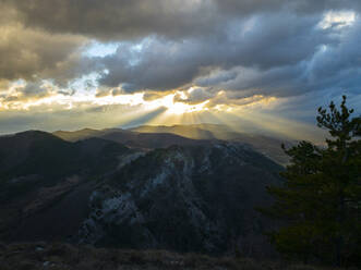 Italien, Provinz Perugia, Gubbio, Untergehende Sonne, die Wolken über dem Apennin durchdringt - LOMF00979