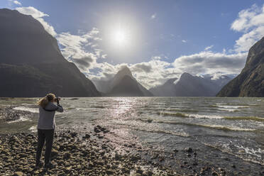 Neuseeland, Touristin beim Fotografieren der malerischen Landschaft des Milford Sound - FOF11614
