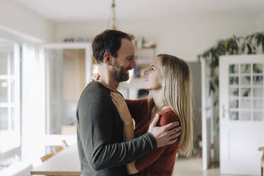 Happy couple embracing in their comfortable home - KNSF07207