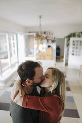Ein glückliches Paar umarmt und küsst sich in seinem gemütlichen Zuhause - KNSF07209