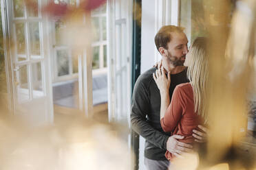 Happy couple embracing and kissing in their comfortable home - KNSF07216