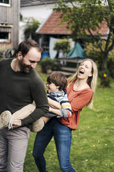 Parents and son having fun, playing in the garden - KNSF07238