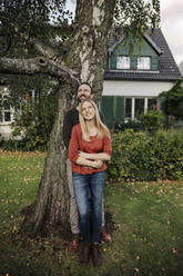 Verliebtes Paar, das im Garten seines neuen Hauses steht und nach oben schaut - KNSF07250