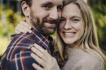 Happy couple embracing in garden, portrait - KNSF07257