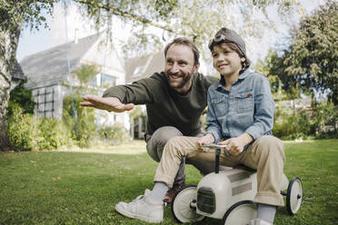 Vater und Sohn spielen mit Spielzeugauto im Garten - KNSF07329