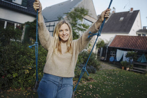 Blonde Frau schwingt in ihrem Garten - KNSF07336