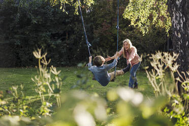 Sohn schaukelt im Garten mit seiner Mutter - KNSF07348