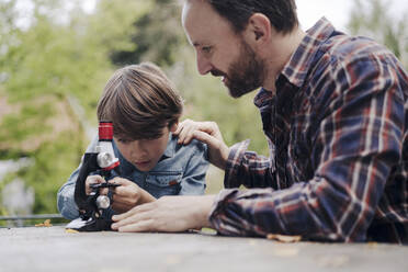 Vater und Sohn betrachten Objekte unter einem Mikroskop - KNSF07350