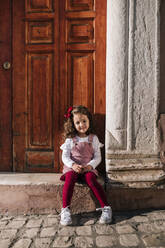 Portrait of smiling girl sitting on front stoop - GRCF00115