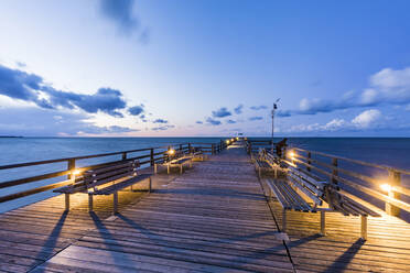 Deutschland, Mecklenburg-Vorpommern, Prerow, Beleuchtete Seebrücke in der Abenddämmerung mit klarer Horizontlinie über der Ostsee im Hintergrund - WDF05678