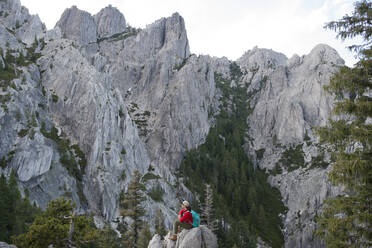 Seitenansicht einer Wanderin, die auf einem Felsen sitzend die Castle Crags betrachtet - CAVF73557