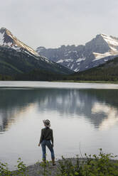 Rückansicht einer Wanderin, die am Ufer des Swiftcurrent Lake steht und die Aussicht genießt - CAVF73558