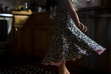 Midsection of girl spinning around at home in darkroom - CAVF73579