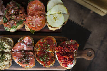 Overhead view of bruschettas on cutting board at table in restaurant - CAVF73658