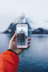 Nahaufnahme eines Touristen, der ein Smartphone-Foto in Hamnoy, Lofoten, Norwegen, aufnimmt - DGOF00064