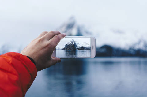 Nahaufnahme eines Touristen, der ein Smartphone-Foto in Hamnoy, Lofoten, Norwegen, aufnimmt, lizenzfreies Stockfoto