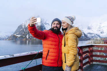 Tourist couple taking a selfie at Hamnoy, Lofoten, Norway - DGOF00082