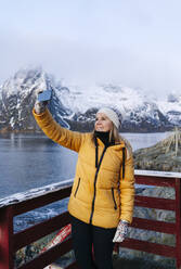 Lächelnder Tourist bei einem Selfie in Hamnoy, Lofoten, Norwegen - DGOF00087