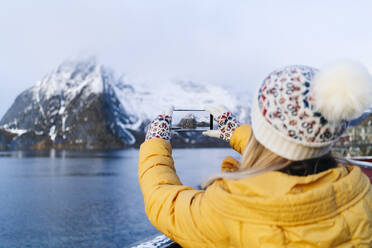 Tourist macht ein Smartphone-Foto in Hamnoy, Lofoten, Norwegen - DGOF00090