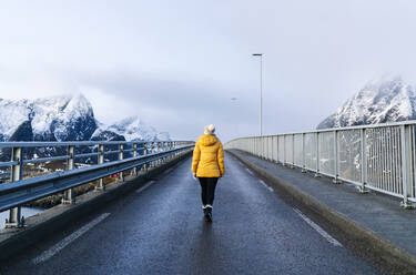Tourist beim Überqueren einer Brücke in Hamnoy, Lofoten, Norwegen - DGOF00093