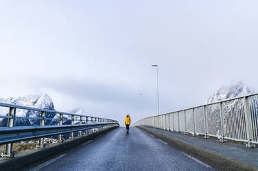Tourist beim Überqueren einer Brücke in Hamnoy, Lofoten, Norwegen - DGOF00094