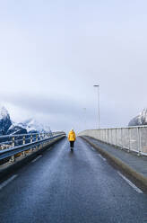 Tourist beim Überqueren einer Brücke in Hamnoy, Lofoten, Norwegen - DGOF00095