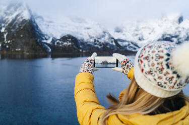 Tourist macht ein Smartphone-Foto in Hamnoy, Lofoten, Norwegen - DGOF00099