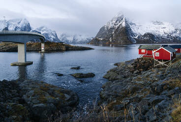 Brücke und rote Hütten an der Küste, Hamnoy, Lofoten, Norwegen - DGOF00102