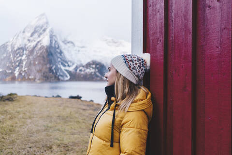 Lächelnder Tourist lehnt an einer Hütte in Hamnoy, Lofoten, Norwegen, lizenzfreies Stockfoto