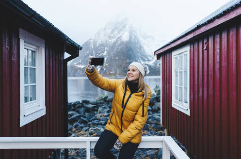 Tourist macht ein Selfie auf einer Veranda in Hamnoy, Lofoten, Norwegen - DGOF00116