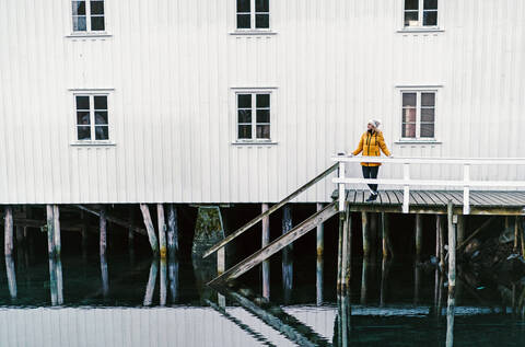 Tourist auf einem Steg am Wasser in Hamnoy, Lofoten, Norwegen, lizenzfreies Stockfoto