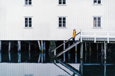 Tourist auf einem Steg am Wasser in Hamnoy, Lofoten, Norwegen - DGOF00126