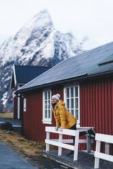 Tourist auf einer Veranda in Hamnoy, Lofoten, Norwegen - DGOF00132