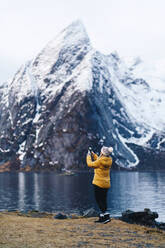 Tourist macht ein Smartphone-Foto in Hamnoy, Lofoten, Norwegen - DGOF00134