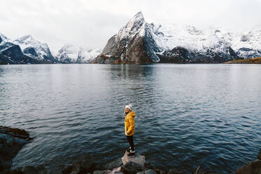 Happy tourist standing on a rock at Hamnoy, Lofoten, Norway - DGOF00148