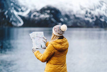 Tourist beim Lesen einer Karte an der Küste in Hamnoy, Lofoten, Norwegen - DGOF00151