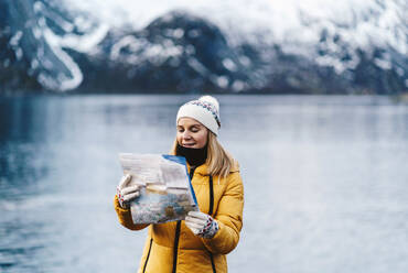 Tourist beim Lesen einer Karte an der Küste in Hamnoy, Lofoten, Norwegen - DGOF00152