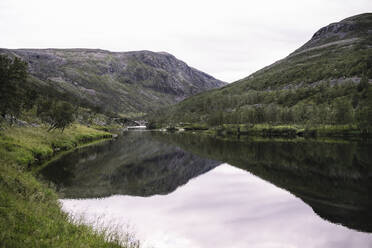 Landschaftsbild eines breiten Flusses und Spiegelung von Bergen, Lakselv, Norwegen - DHEF00070