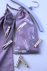 Deutschland, Studioaufnahme einer lila Stofftasche mit Wäscheklammern - GISF00499