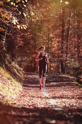 Frau joggt im Herbstwald - DHEF00083