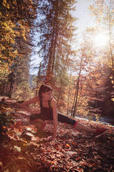 Frau beim Joggen im Herbstwald, Stretching zum Aufwärmen - DHEF00090