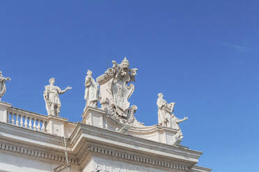 Italy, Rome, Low angle view of sculptures standing on top of colonnade of Saint Peters Square - MMAF01210