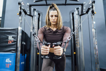 Woman exercising at cable machine in gym - OCMF01006