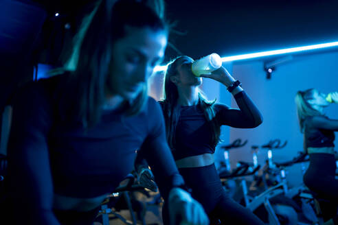 Frau auf Spinning-Rad im Fitnessstudio macht eine Abkühlungspause - OCMF01011