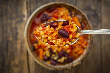 Spoon of vegan chili with red lentils, celery sticks, kidney beans, tomatoes and carrots - LVF08574